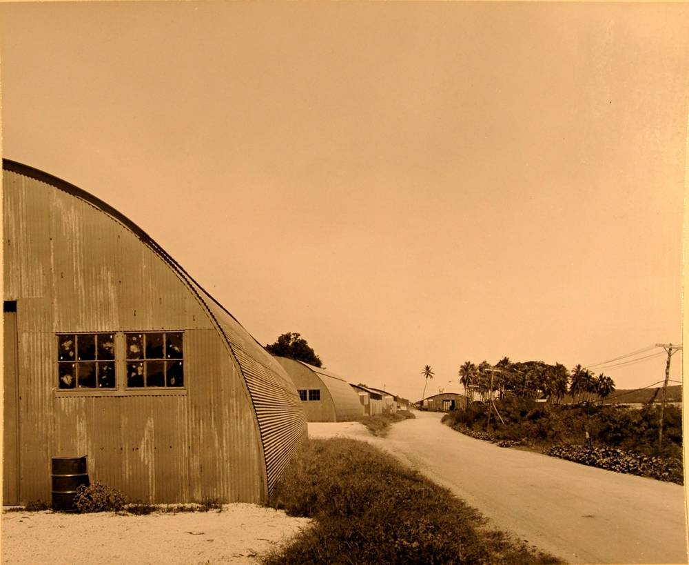 Row of corrugated Quonset warehouses along a road